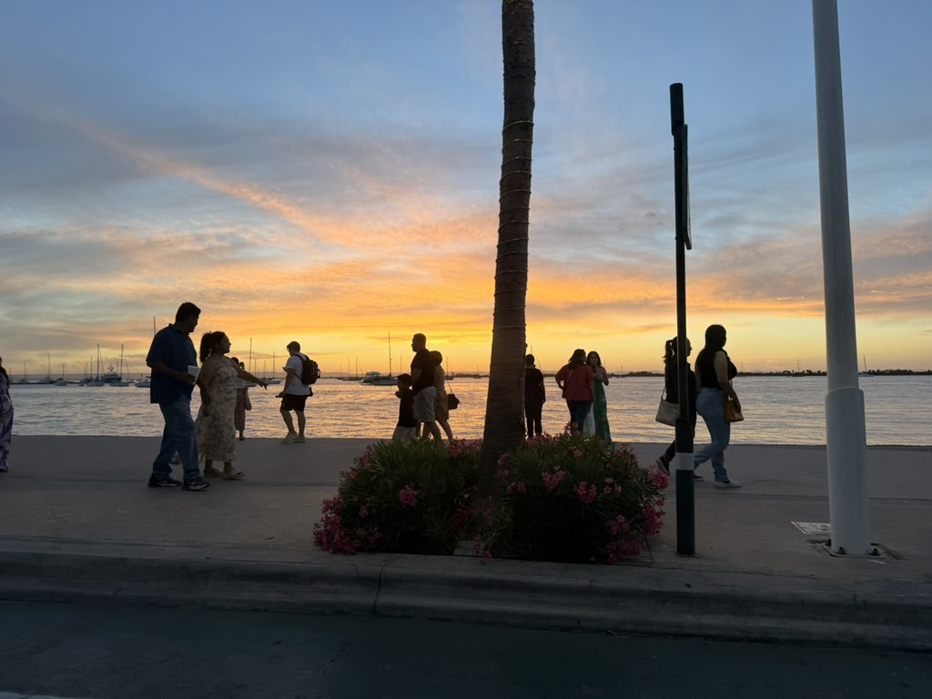Silhouettes strolling the La Paz malecón as the sun sets over the marina
